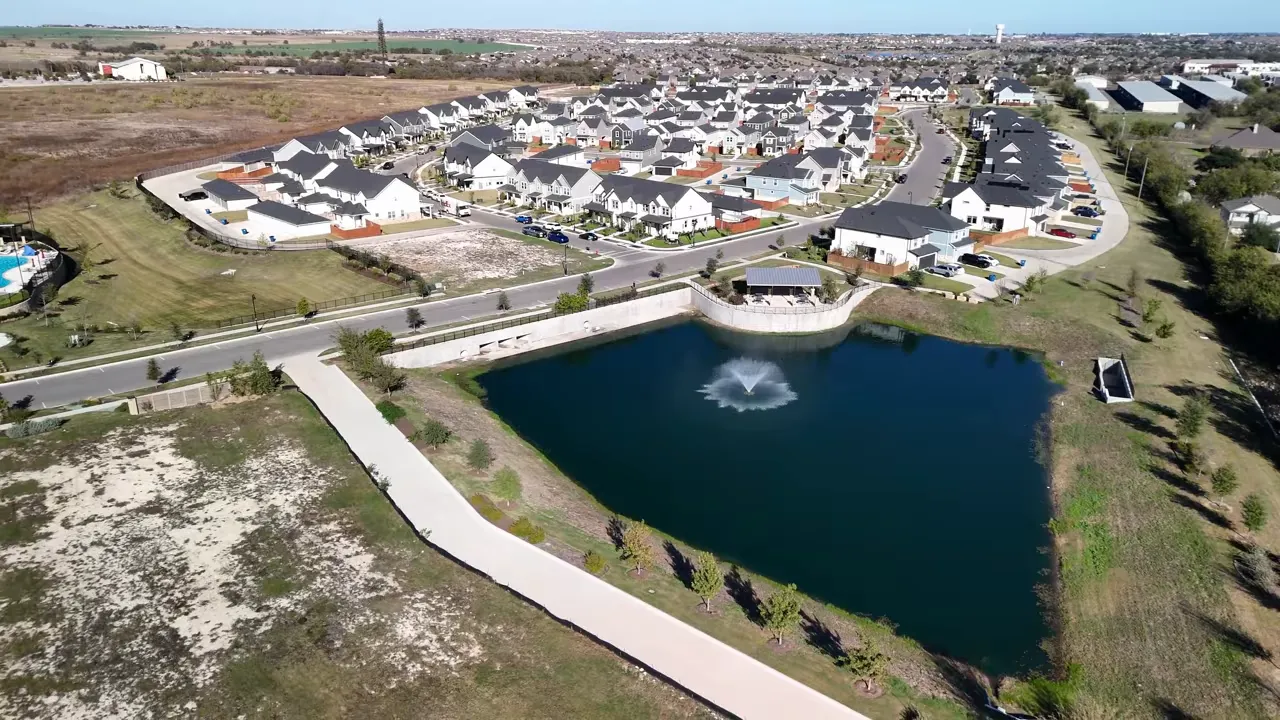 Aerial view of an Austin suburb community with homes and a pond