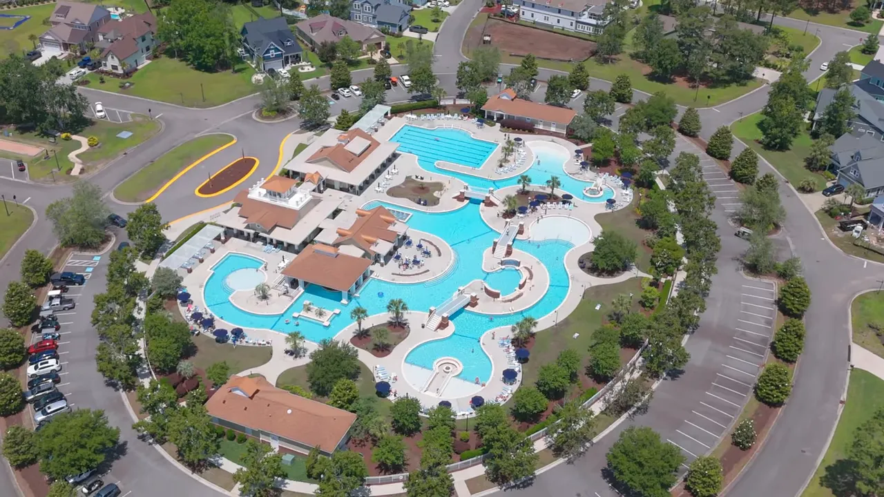 High-resolution aerial of the community amenity center showing interconnected pools, lap pool and surrounding parking