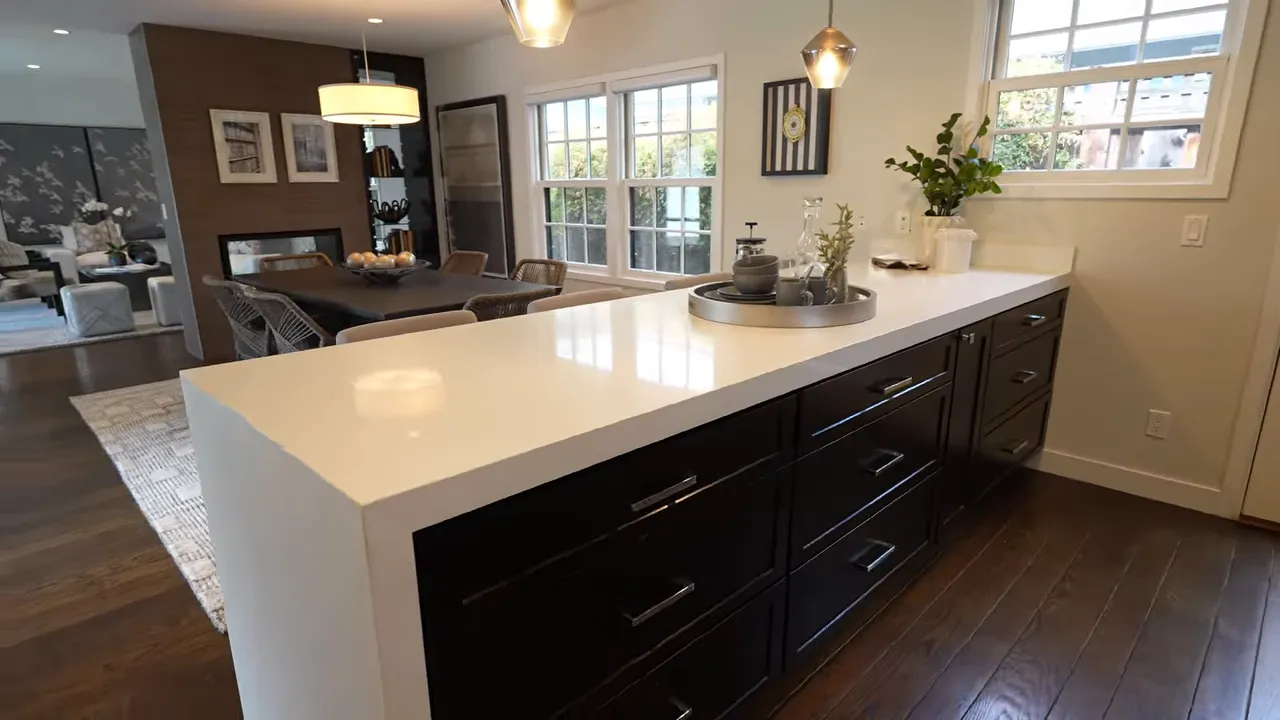 Modern kitchen with large white island dark cabinets and stainless steel range