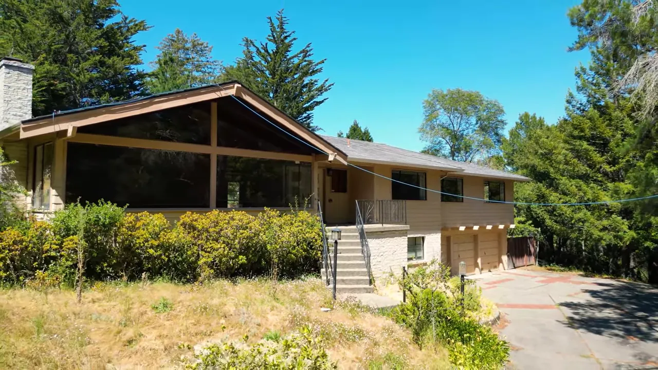 clean shot of a single-story mid-century style house with large windows, front steps and driveway