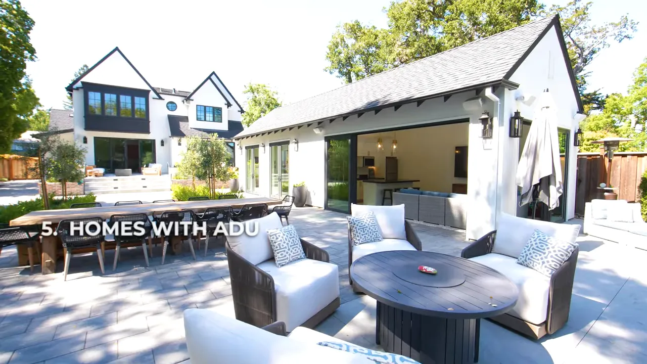 Wide view of a backyard patio and detached accessory dwelling unit with sliding glass doors and a long outdoor dining table; on-screen text reads '5. HOMES WITH ADU'.