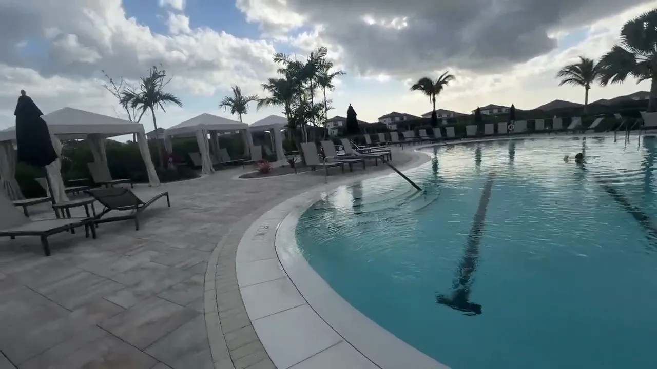 Large resort style pool with curved edges lounge chairs and palm trees