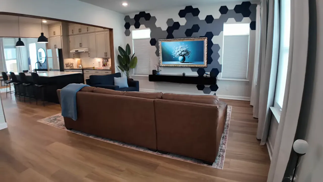 Open living room with stairs, sofa, wood flooring, and view toward kitchen