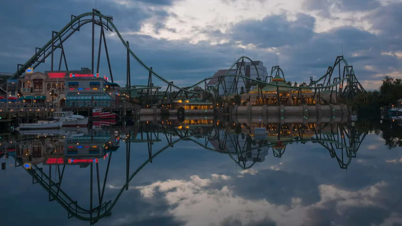Amusement park roller coaster reflected in calm water at dusk