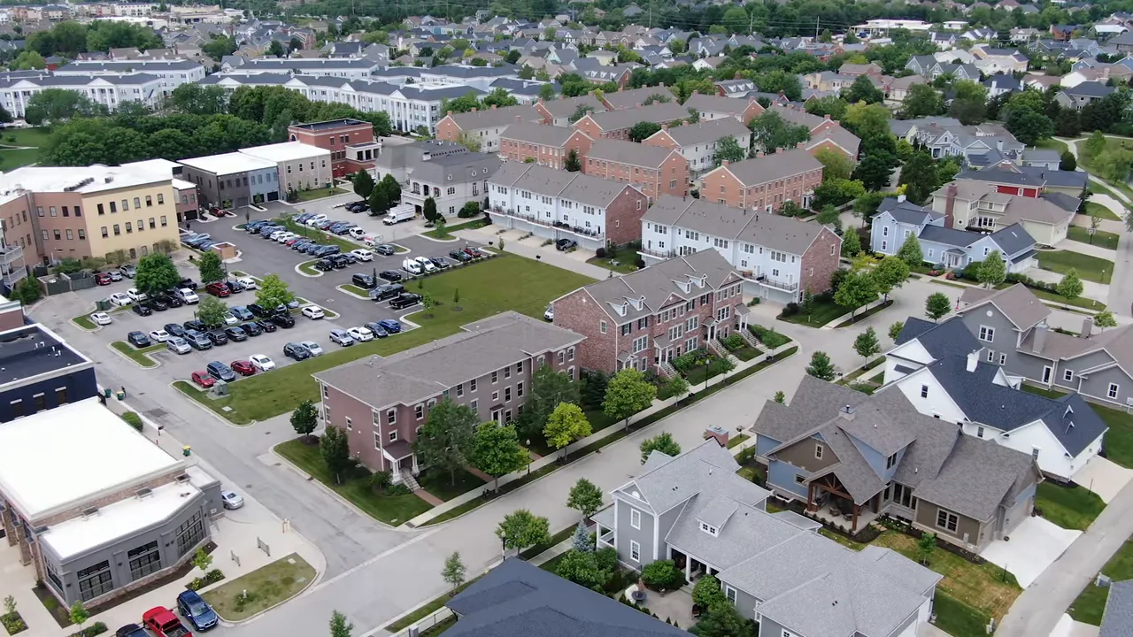 Aerial view of a suburban Indianapolis neighborhood with houses, townhomes, streets, parking lots and green spaces, illustrating neighborhood layout and daily routines.
