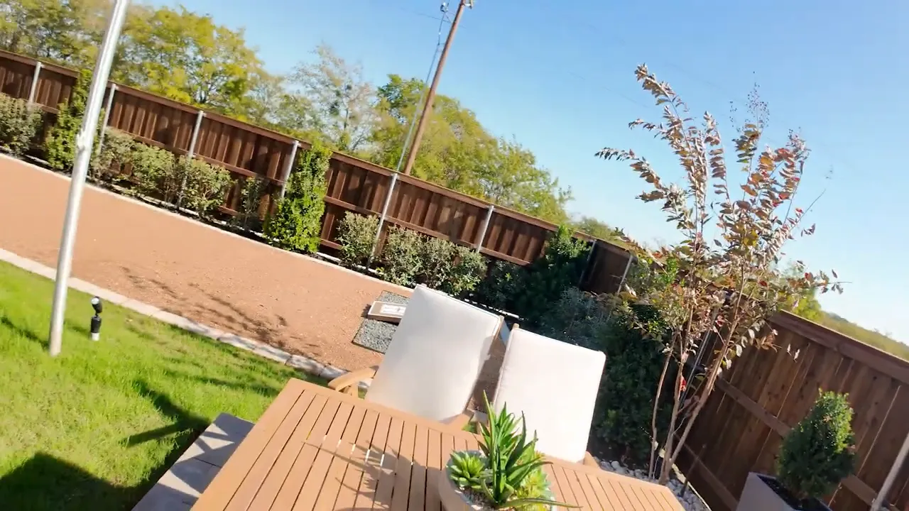 Patio table and chairs with fenced backyard and landscaping showing yard depth