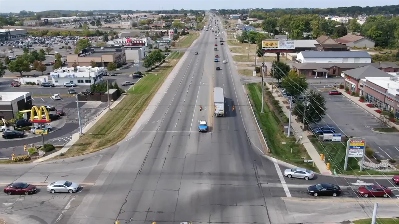 Aerial view of a wide commercial roadway with traffic and businesses