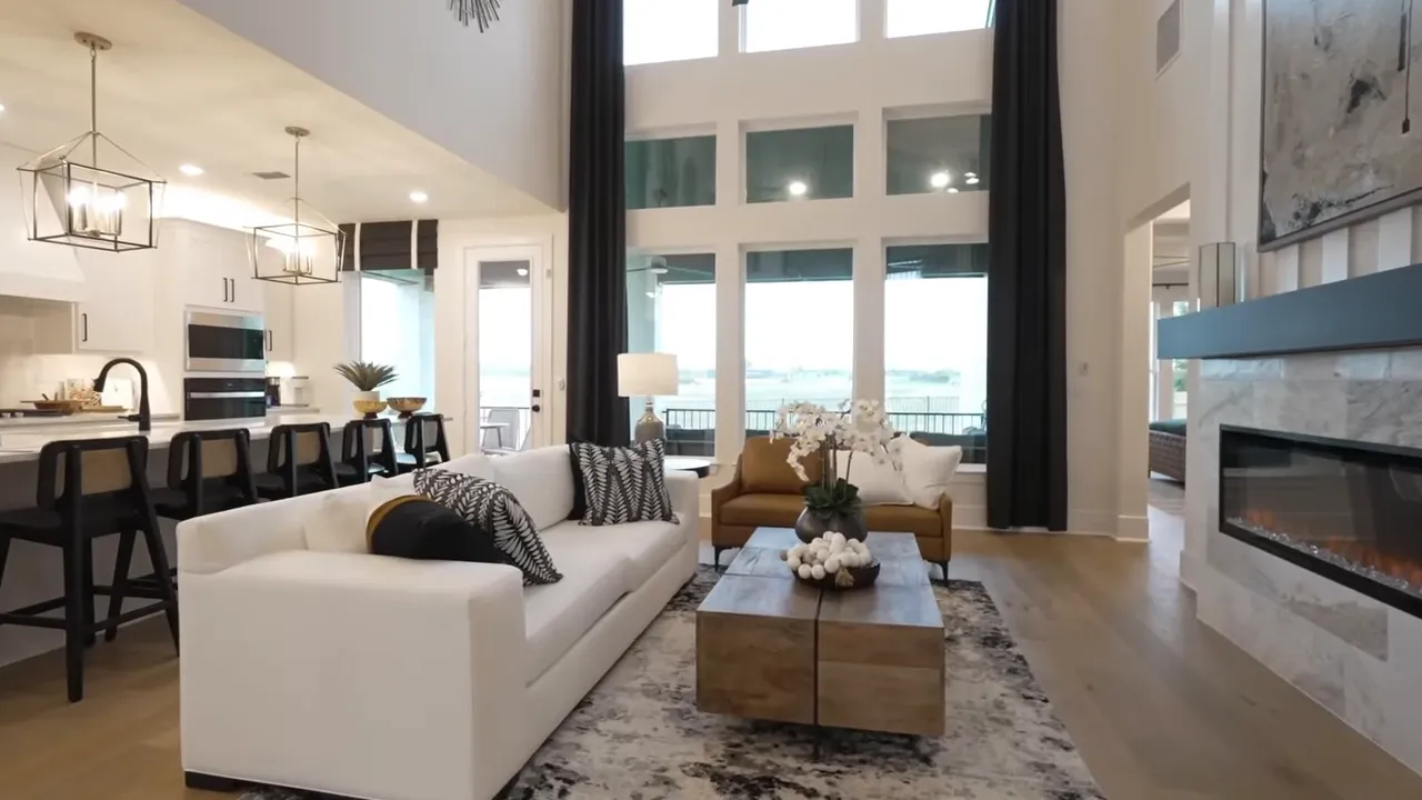 Living room with white sofa, coffee table, floor-to-ceiling windows and kitchen island