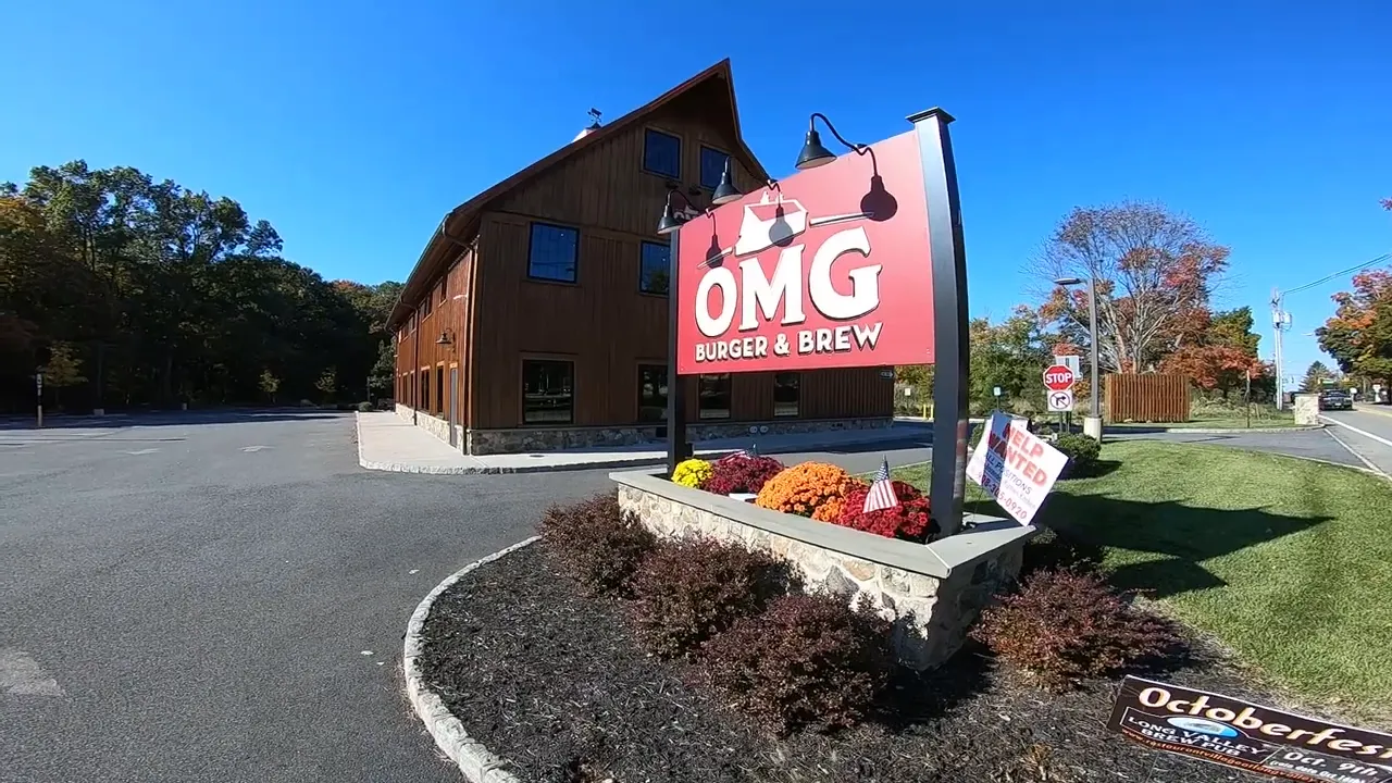 Sign for OMG Burger and Brew in front of a brown building beside a parking area