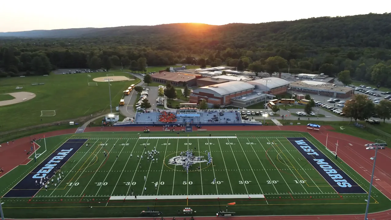 Football field and school campus at sunset with surrounding sports facilities