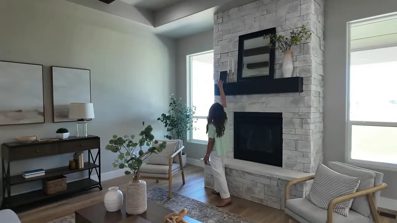 Stone fireplace with black mantel between tall windows in living room