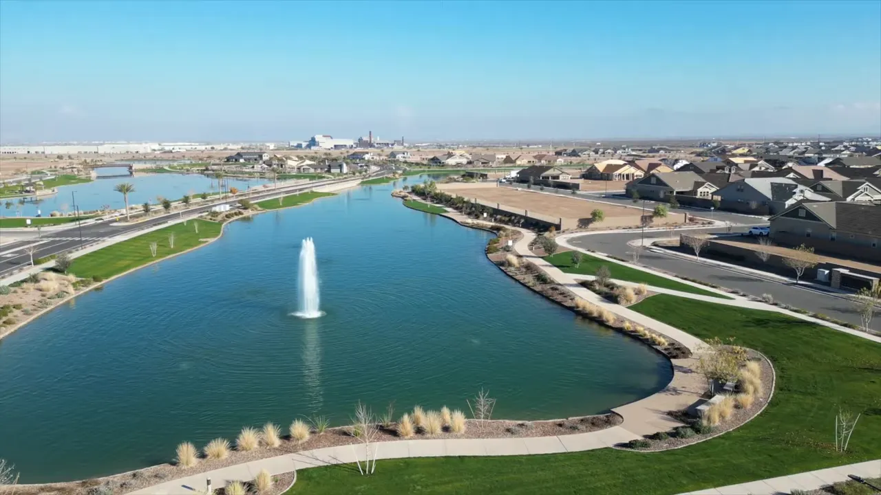 large green lake with fountain walking paths and neighborhood homes around the shoreline