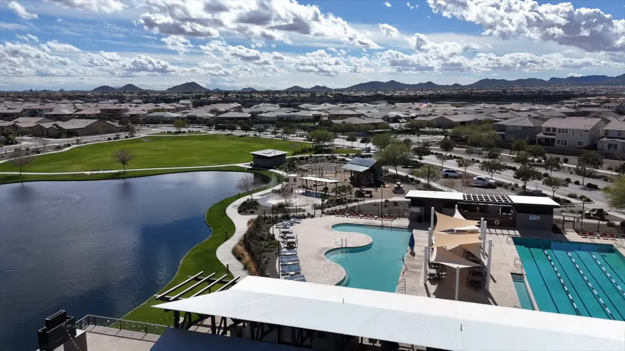large community pool and lap pool beside a lake with walking paths and neighborhood homes