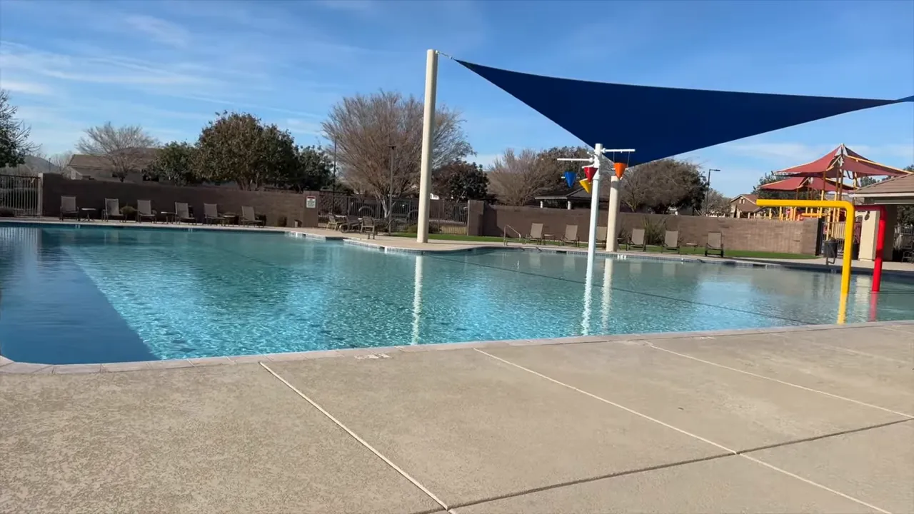community pool with shade sails splash area and seating