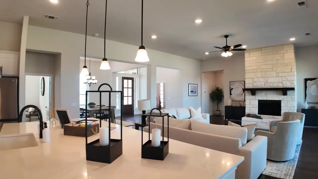 Open living room and kitchen with large island pendant lights and stone fireplace