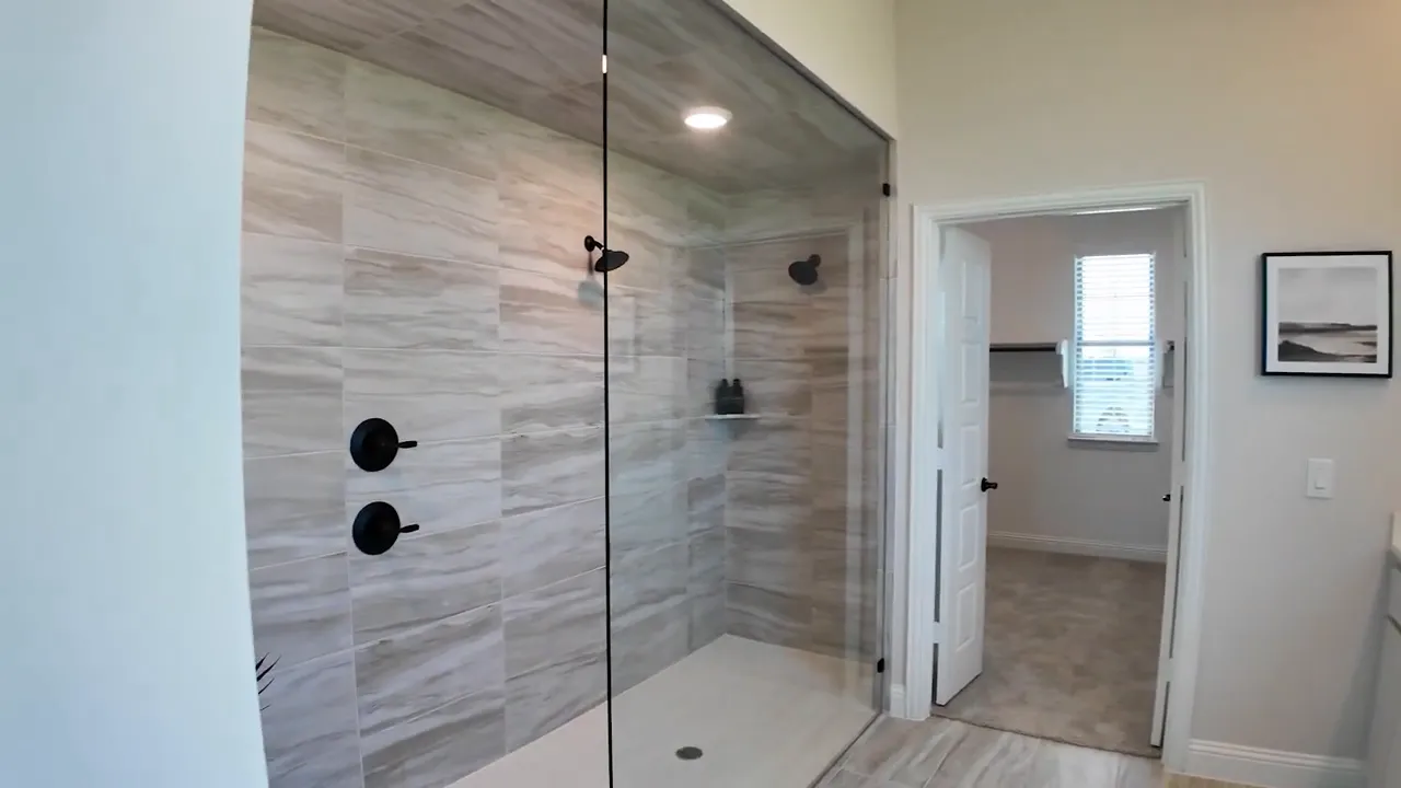 Primary bathroom with double vanity and large frameless glass shower