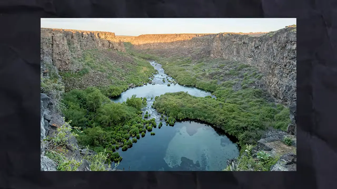 Scenic canyon with a river winding through green vegetation between rock walls
