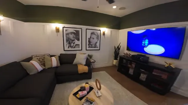 Media room with dark sectional sofa, wall art, ceiling fan, and television