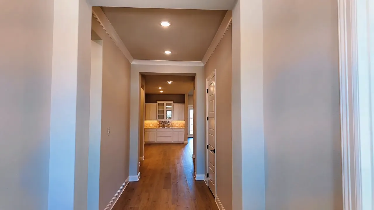 New construction home entry hallway with recessed lighting and view into the kitchen area