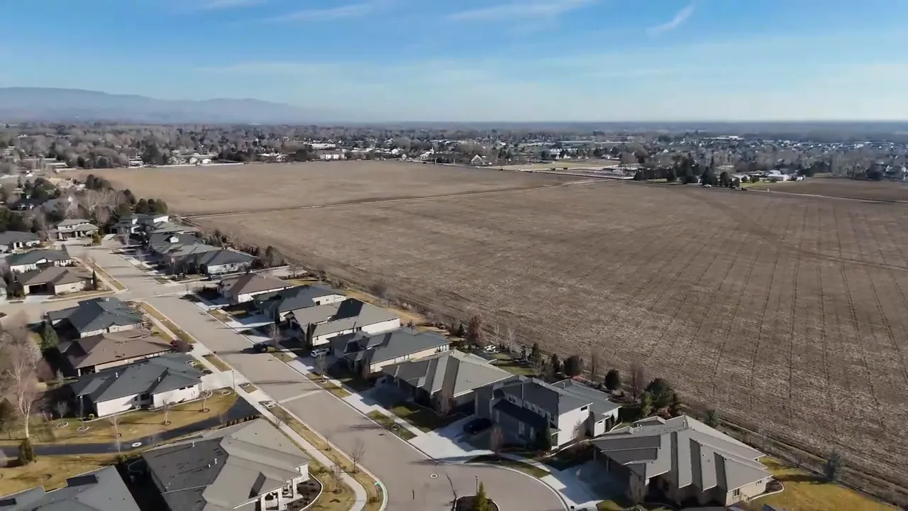 Aerial of a residential neighborhood directly adjacent to large open farmland showing lot separation