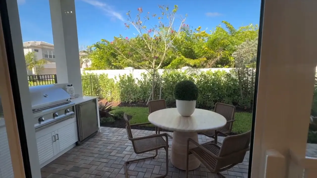 Stellar outdoor dining patio table with grill and landscaped yard at Valencia Sky in Naples FL