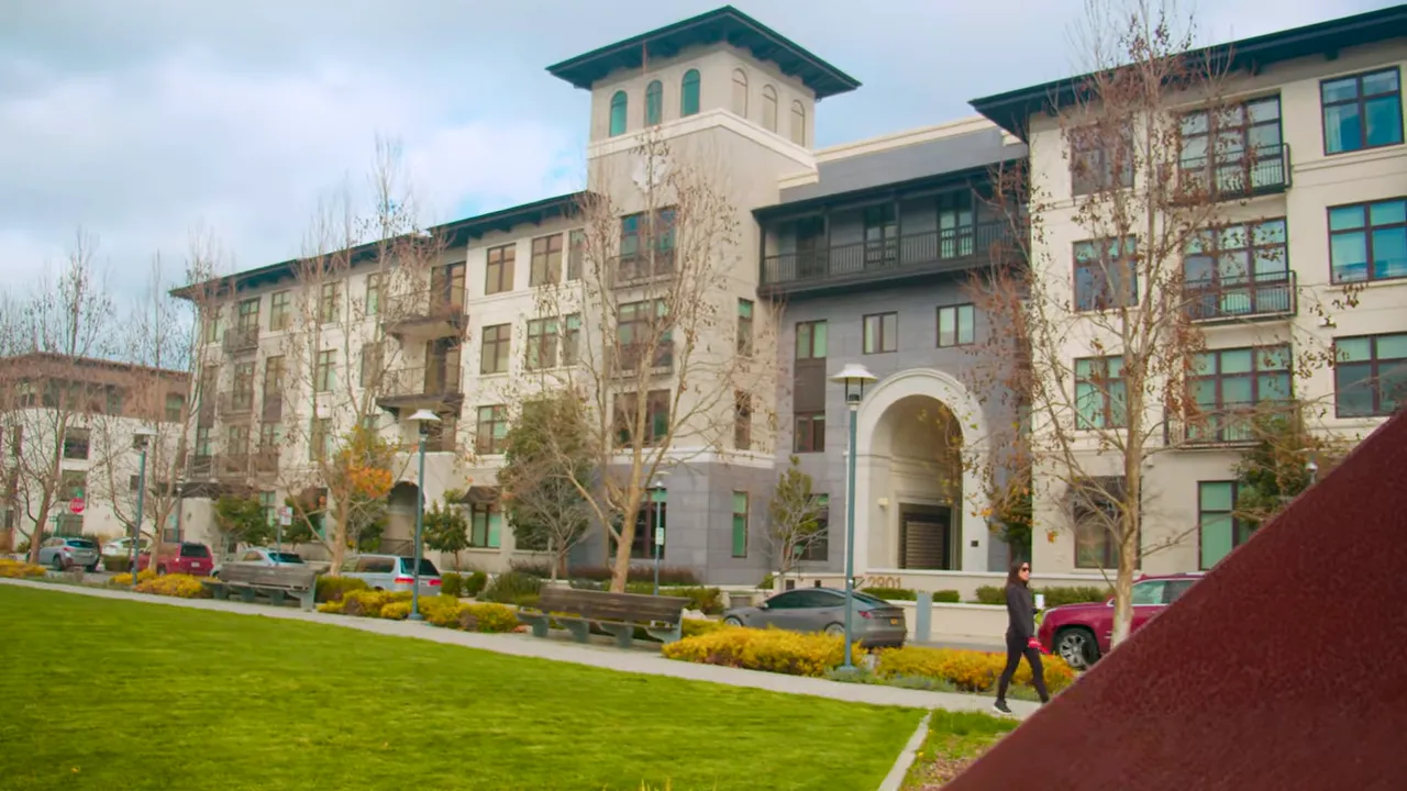 Modern mid-rise condos with a green lawn, benches and a pedestrian path in front