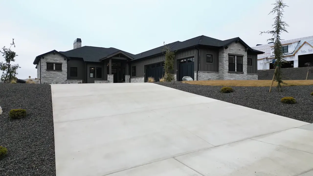 Exterior front view of a single-level home with a long concrete driveway and wide yard area