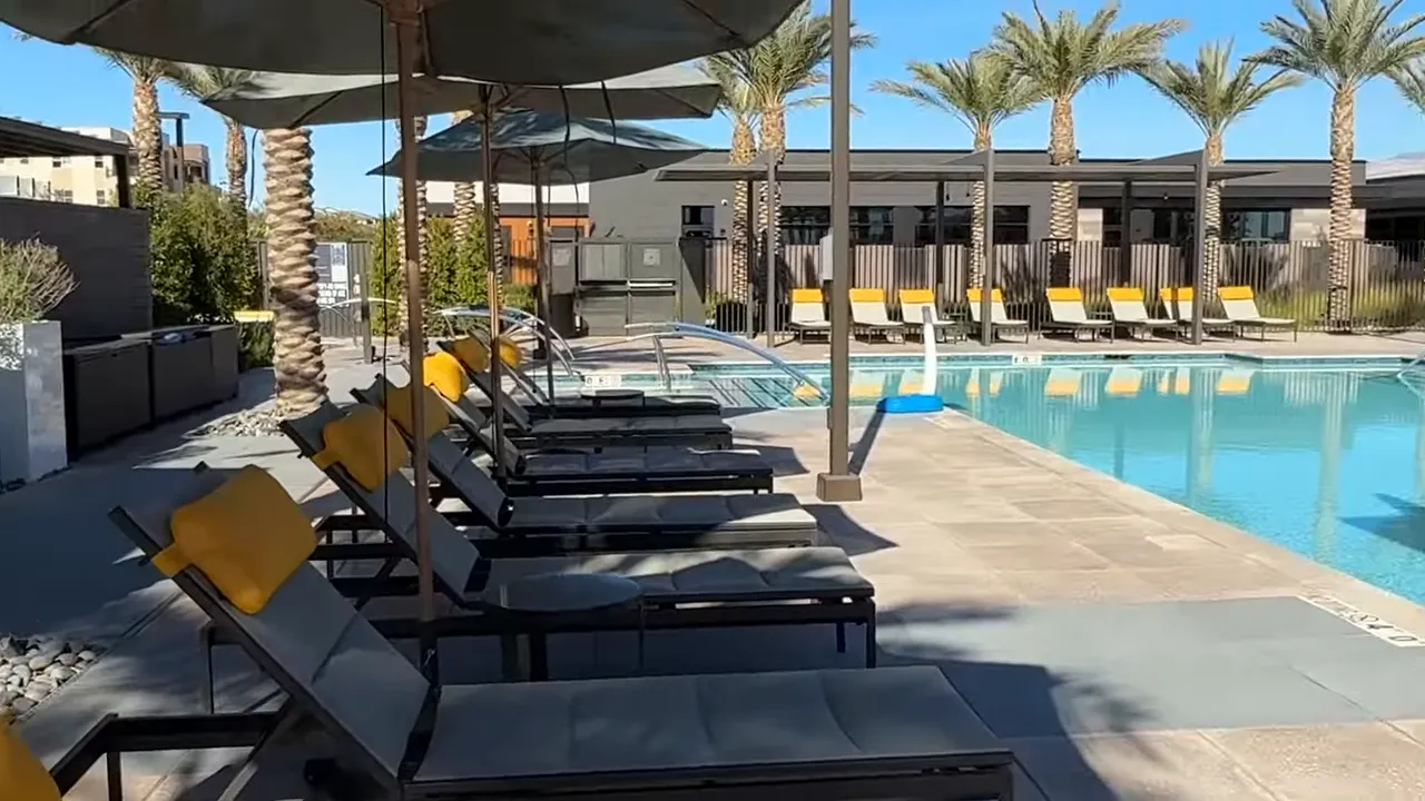 Poolside lounge chairs with yellow cushions beside resort pool