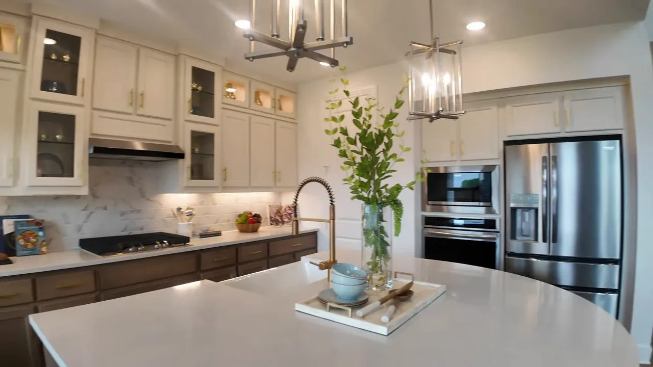 Large kitchen with white island, two tone cabinetry, pendant lights and decorative tray centerpiece