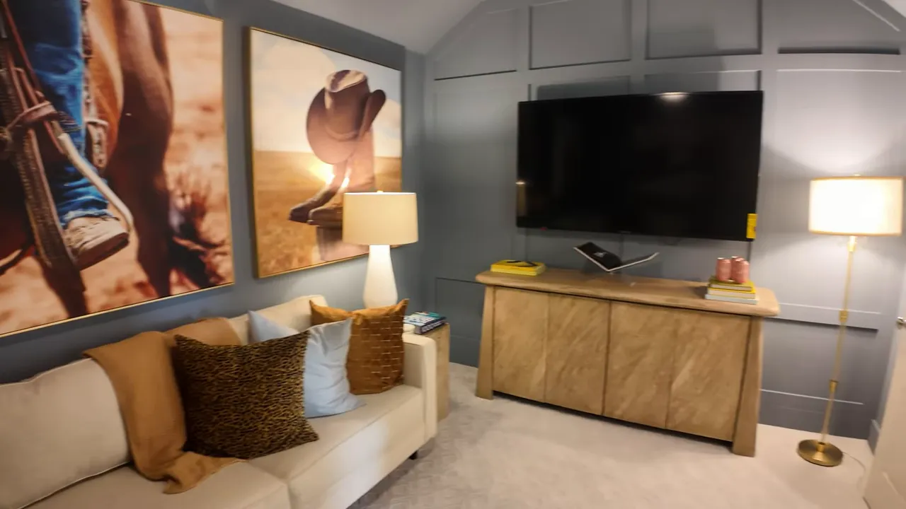 Media room with sectional seating, wall art, lamp and television on cabinet