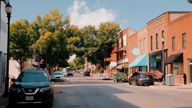 Brick storefronts and parked cars along a tree-lined downtown street