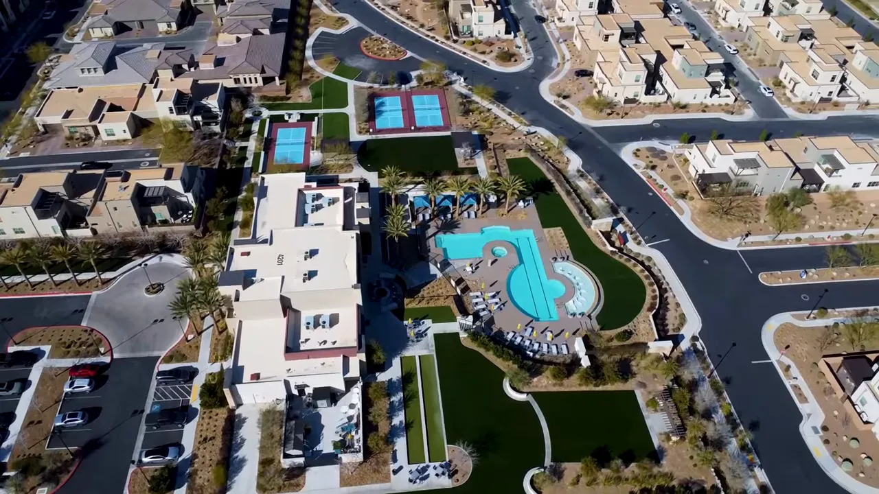 Aerial view of a community clubhouse pool and tennis courts