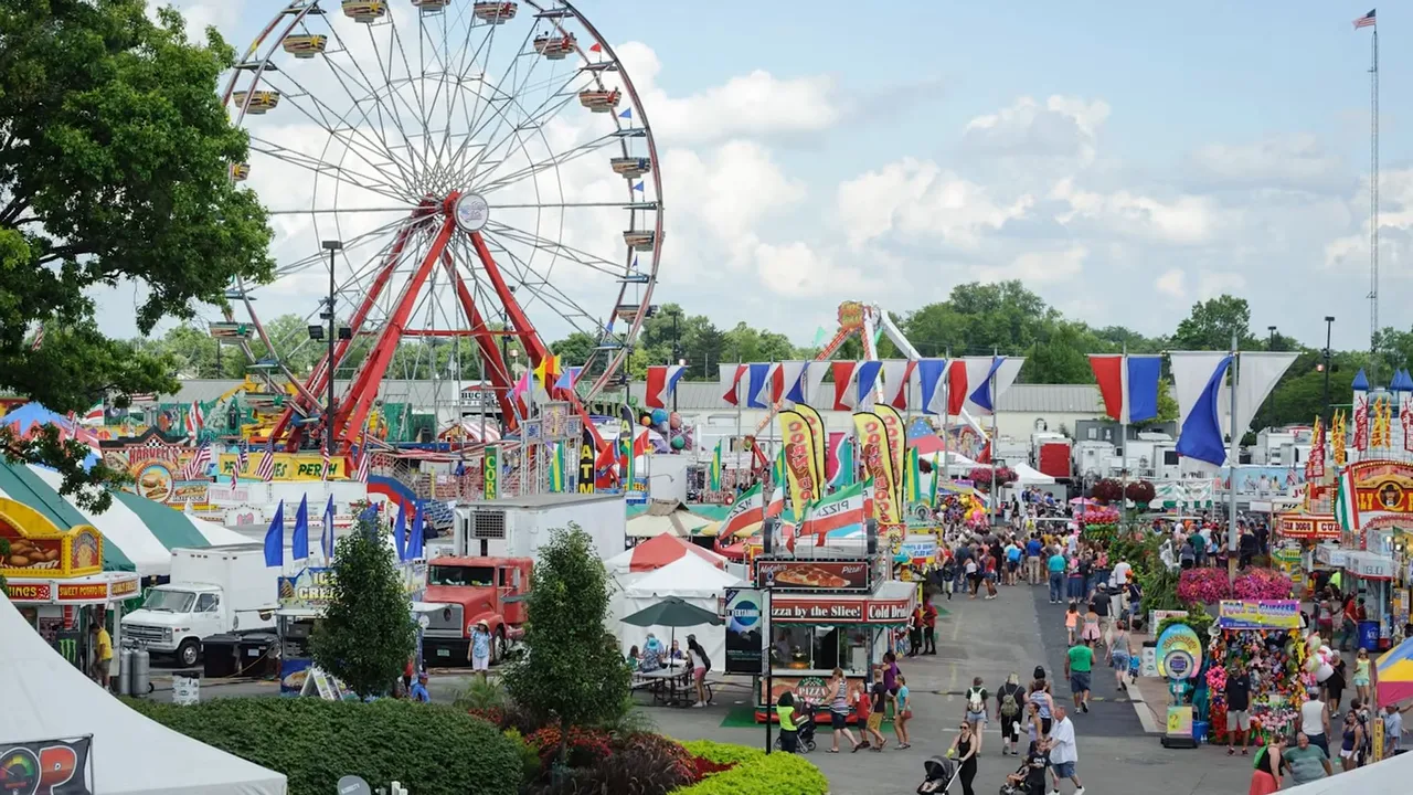 Crowded fairground with ferris wheel and festival tents