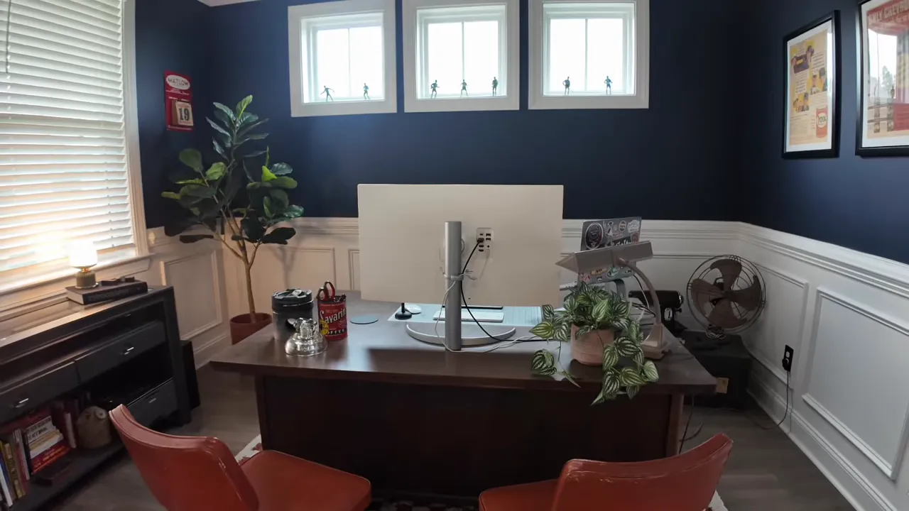 dark blue office with white wainscoting desk red chairs small high windows and modern light fixture