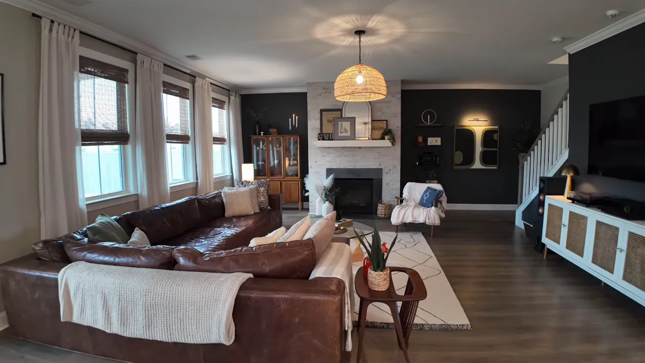 living room with leather sectional fireplace woven pendant light and tv on dark accent wall