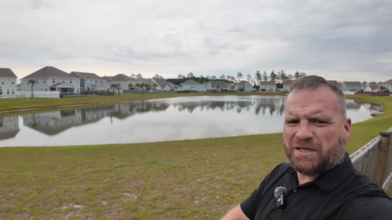 pond behind the backyard with grassy bank and homes across the water
