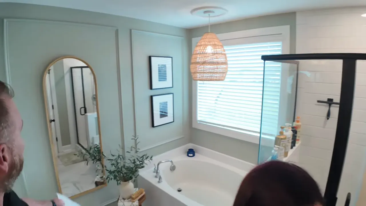 primary bathroom with soaking tub paneled wall arched mirror and woven pendant light