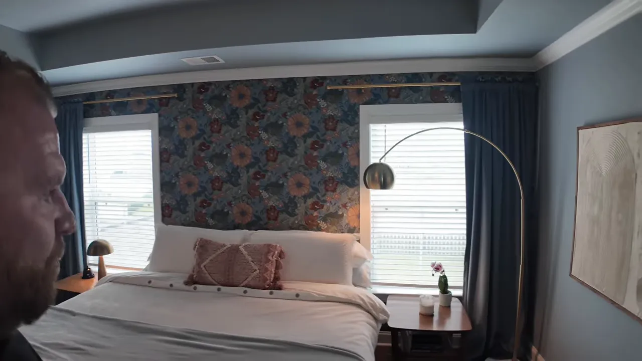 primary bedroom with floral accent wall large bed blue walls and arched floor lamp
