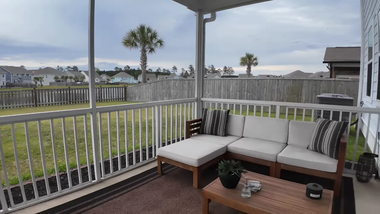 screened porch with sectional seating coffee table and fenced backyard view