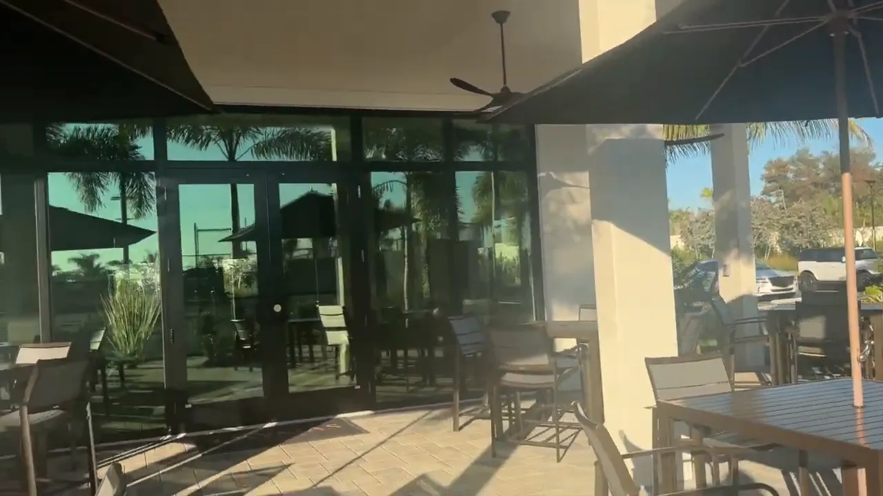 Patio dining tables and umbrellas outside amenity building entrance