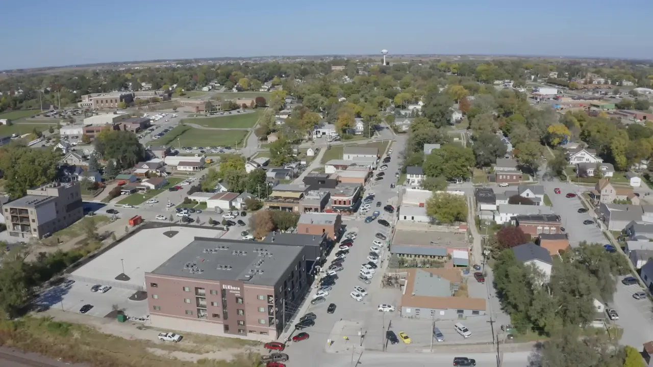 Aerial view of an Omaha neighborhood and small downtown block showing shops, houses and tree canopy