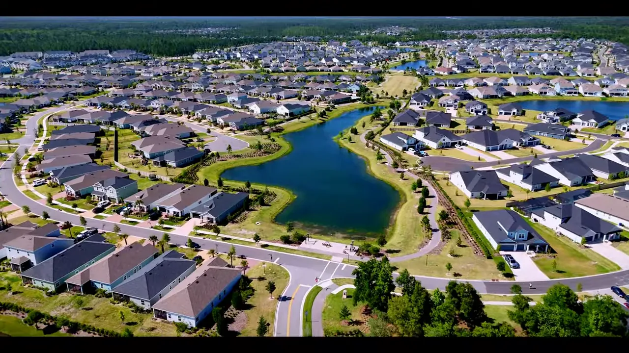 Presenter standing on a wide new sidewalk in front of modern townhomes and street trees in redeveloped downtown Jacksonville.