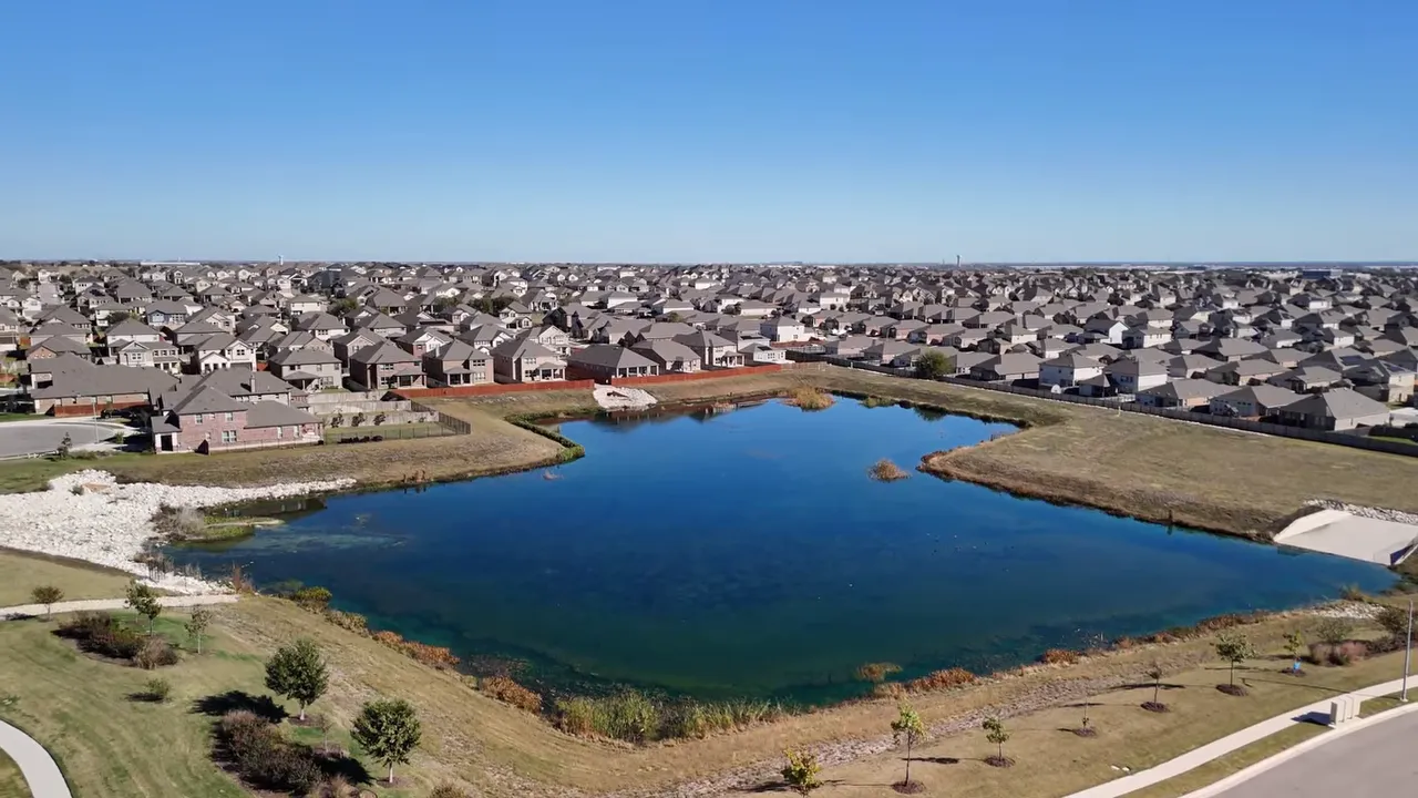 Aerial view of a Round Rock neighborhood with homes surrounding a small lake