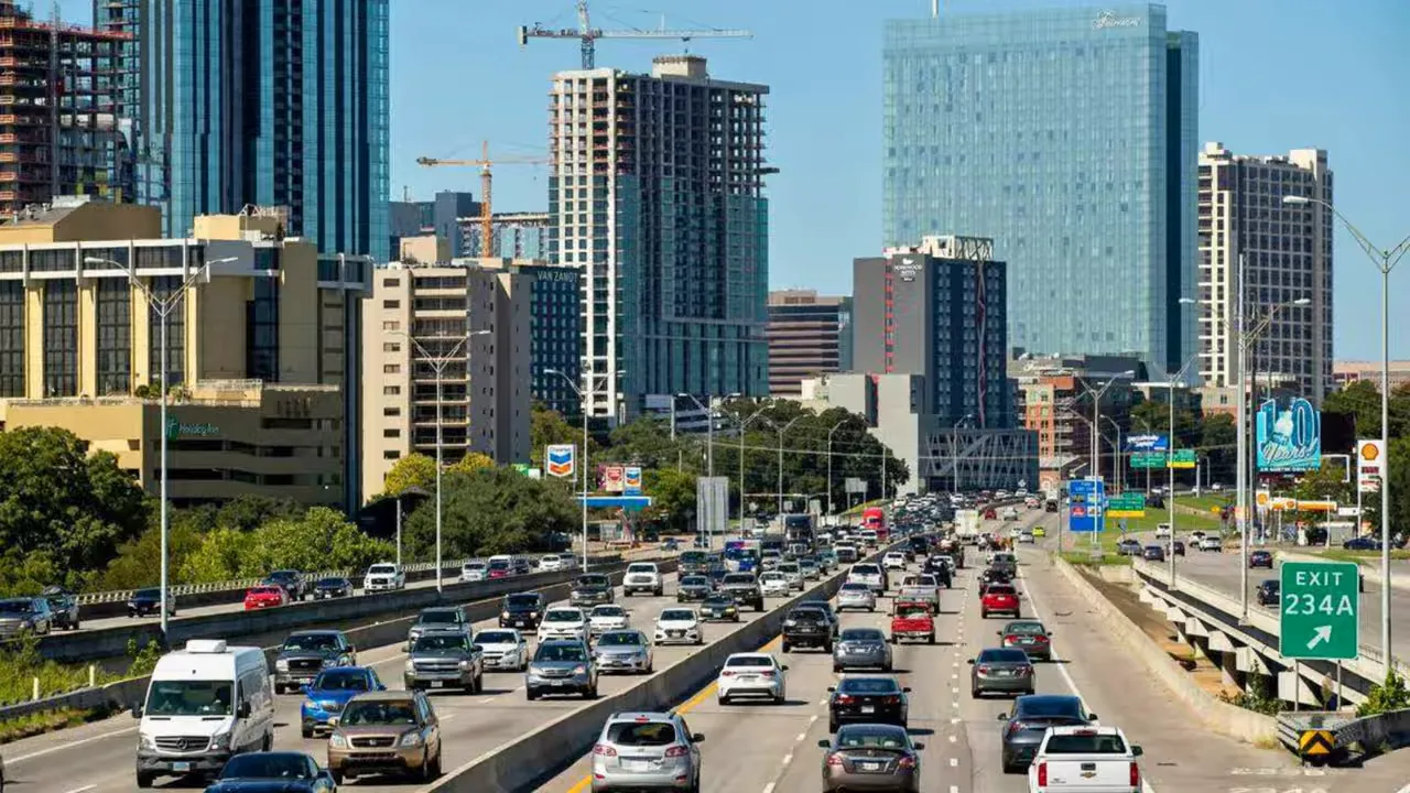 Cars backed up on an Austin-area highway lined with downtown buildings and exit 234A sign