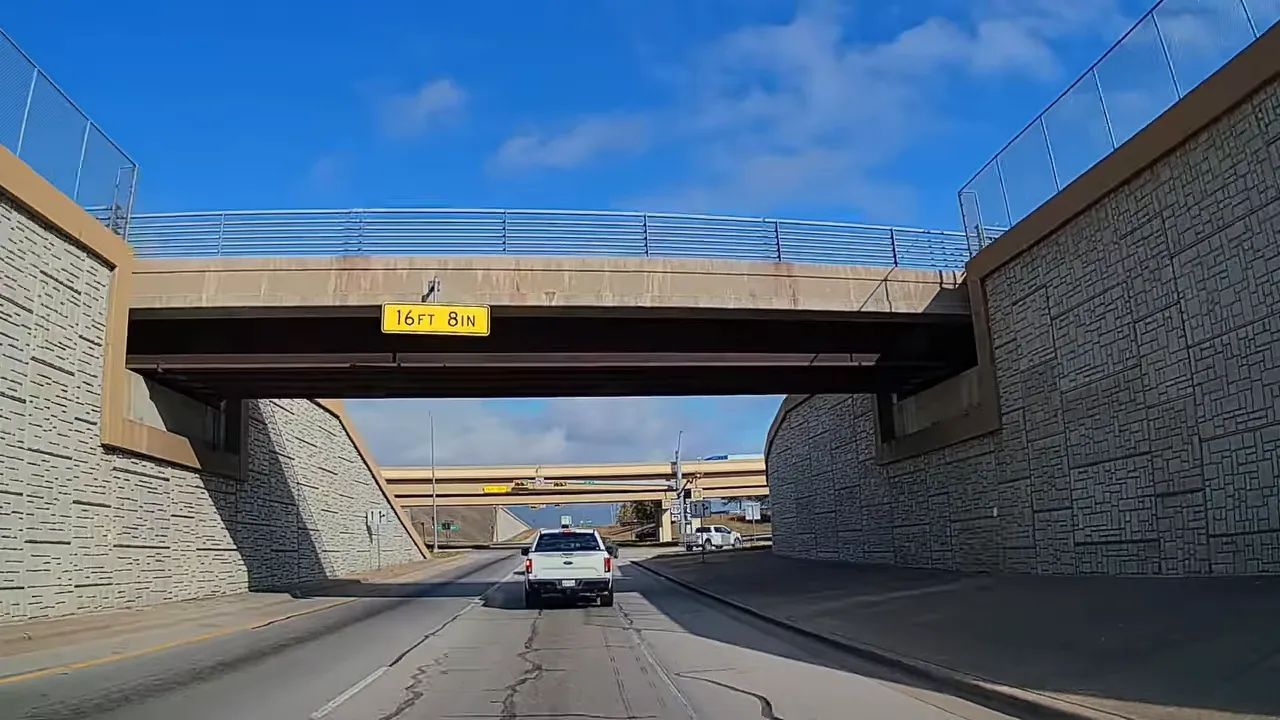 View of a roadway narrowing through a concrete underpass and roadway tunnel-like section