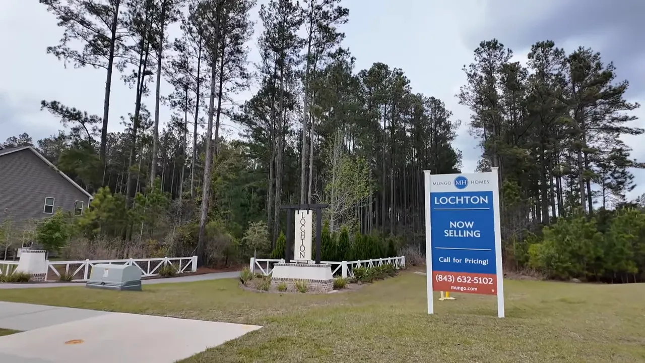 Lockton neighborhood entrance monument and 'Now Selling' sales sign with trees behind