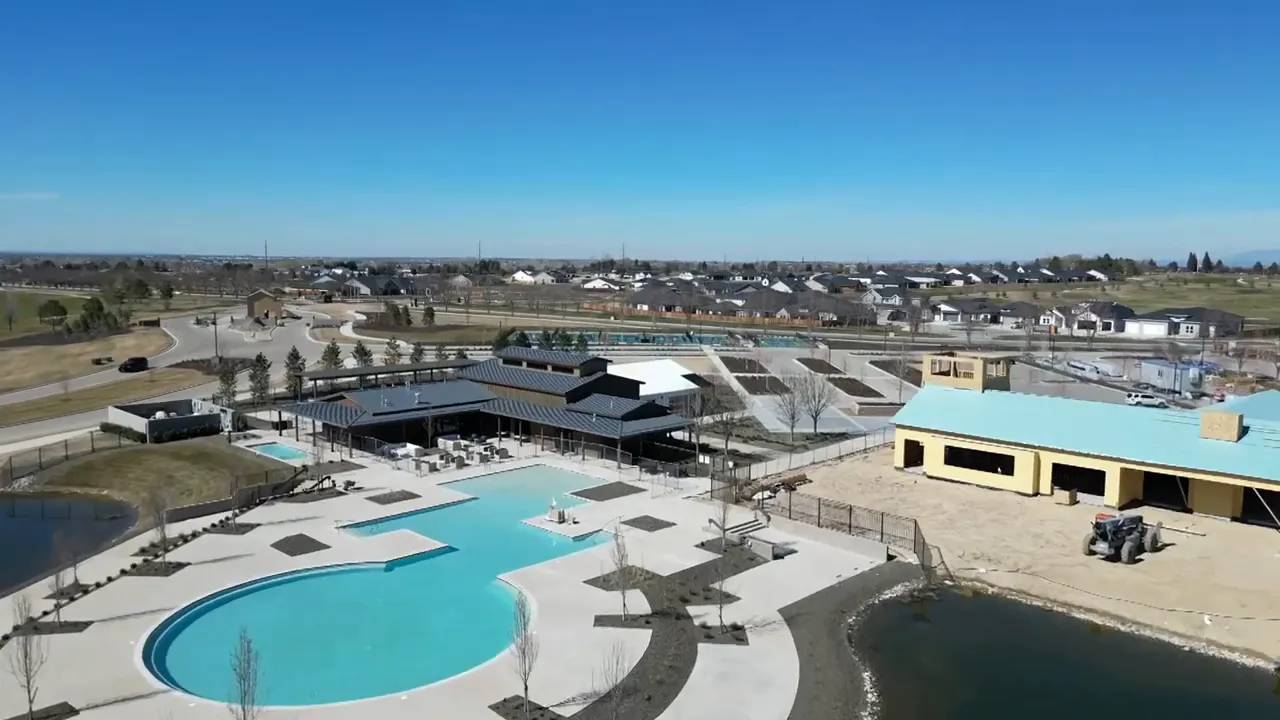 Aerial shot of Valor community showing the clubhouse, large resort-style pool, walkways and nearby construction