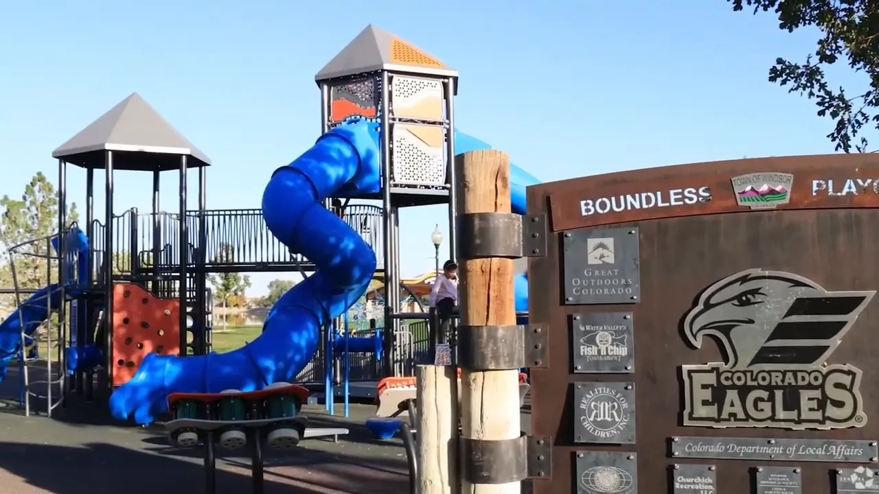 Playground with blue slide and a sign for Boundless Playground Eagles