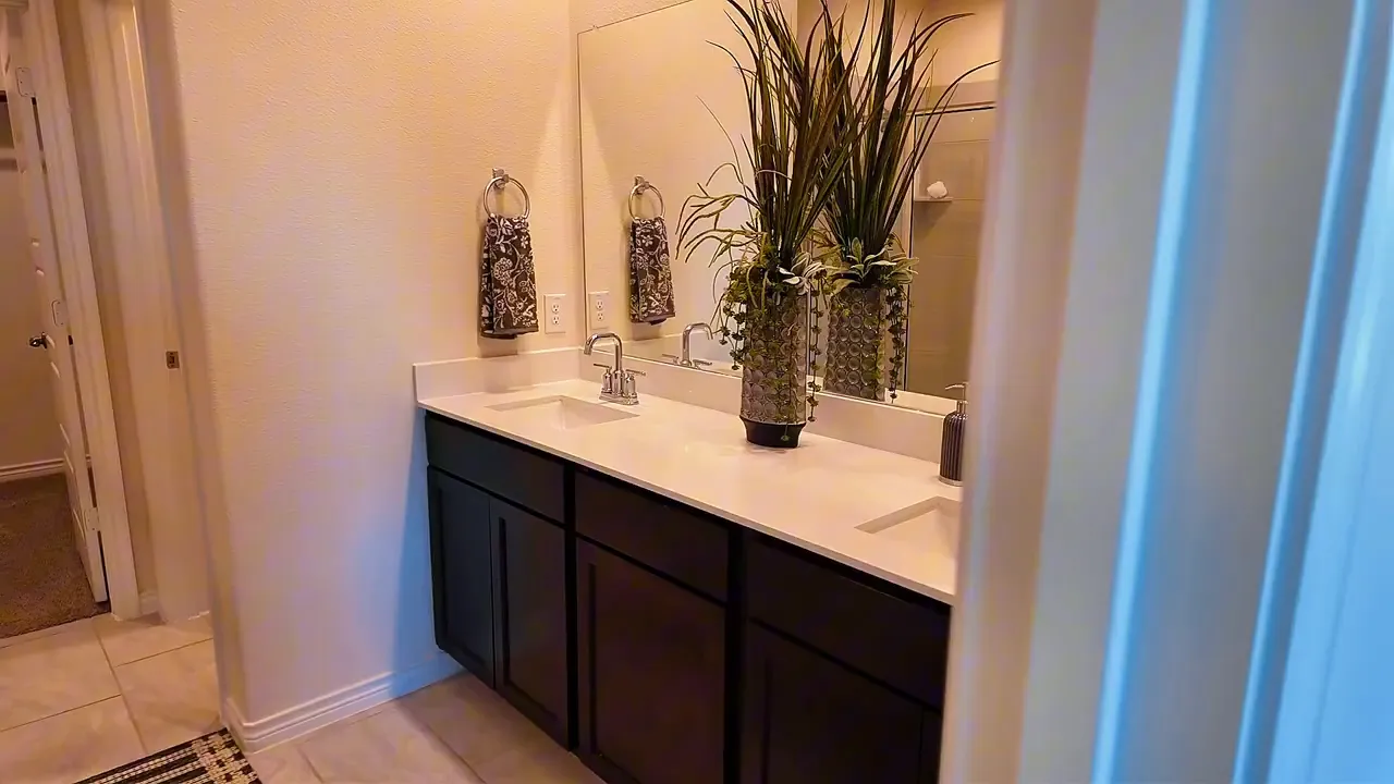 Primary bathroom dual sink vanity with quartz countertop and dark cabinets