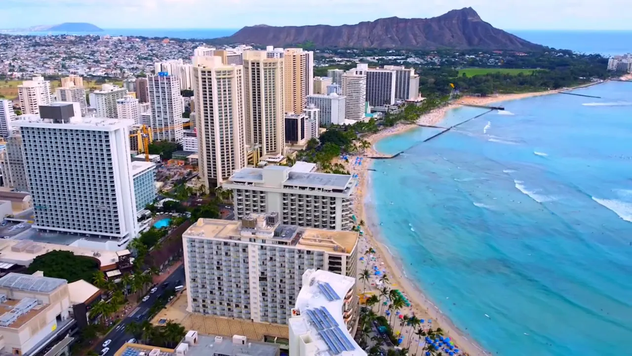 Aerial view of Waikiki coastline showing high-rise buildings, sandy beach and turquoise ocean with Diamond Head